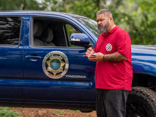 A KT Protection Services protection specialist stands outside his company truck and takes notes while on patrol