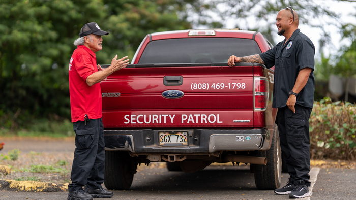 KT Protection Services personnel discuss a patrol while standing near the back of a company truck
